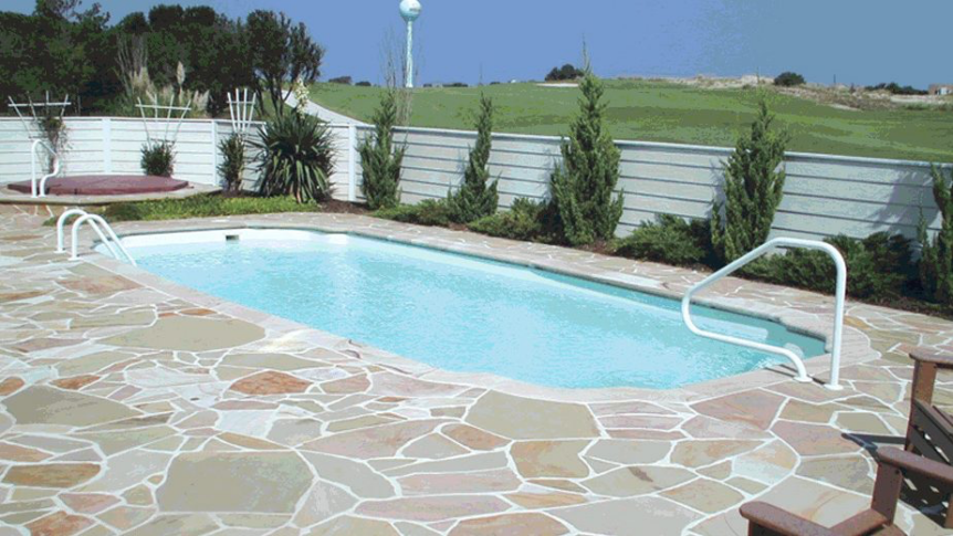 Martinsville medium-sized fiberglass inground pool, surrounded by a stone patio and landscaping.