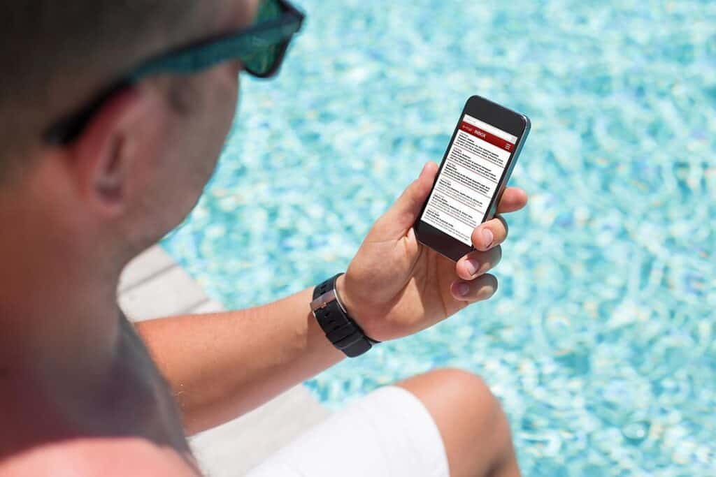 Man sitting by the pool and checking email