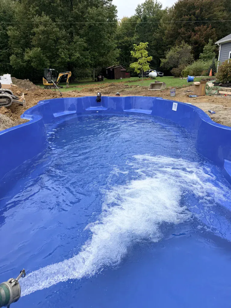 Fiberglass pool shell beginning to take shape in a backyard